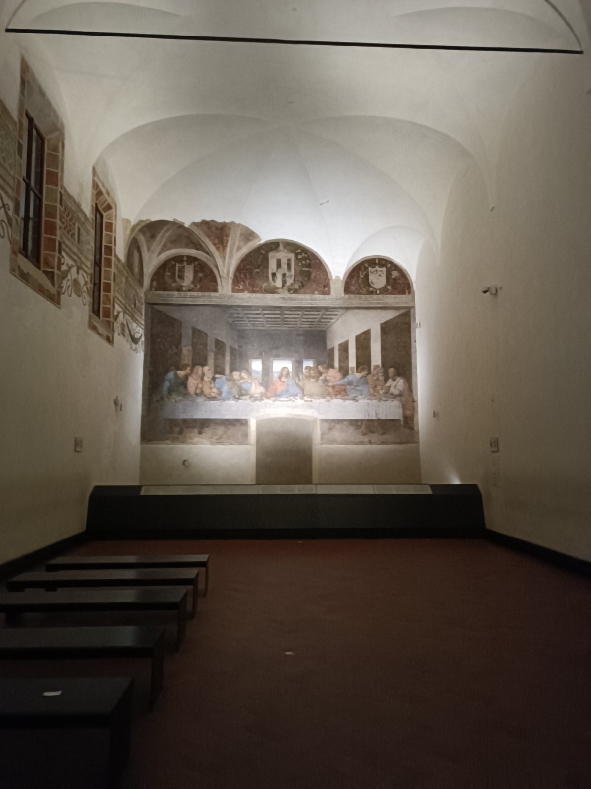 the friars’ dining hall at santa maria delle grazie in milan: a long vaulted room with the last supper on its end wall, and under the middle of the painting the outline of a doorway, walled up, from the floor up into the table
